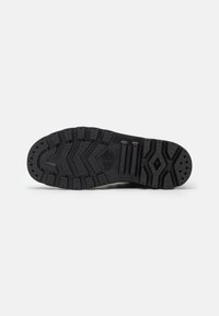Suela de zapato de goma negra con un patrón texturizado, que presenta surcos profundos y áreas elevadas para tracción y flexibilidad.