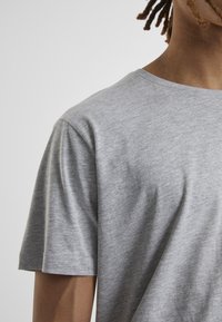 Tricou din bumbac gri cu guler rotund și mâneci scurte, având o textură netedă și un model subtil de heather.