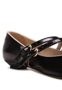 Chaussure plate en cuir verni noir avec deux fines lanières doubles fermées par de petites boucles dorées, doublure intérieure beige et talon bas.