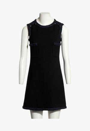 Robe noire sans manches longueur genou avec deux poches sur le devant et finition texturée sur l'encolure, les emmanchures et l'ourlet sur un mannequin blanc.