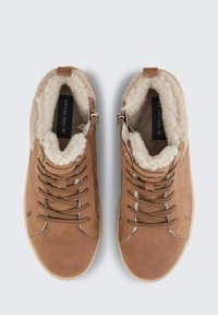 Braune Wildleder- Stiefeletten mit einem flauschigen beigen Innenfutter, runder Spitze, strukturierten Schnürsenkeln und seitlichen Reißverschlüssen für ein einfaches Anziehen. Glatte Gummisohlen.