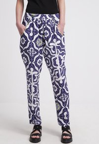 Lätta, mönstrade byxor i marinblått och vitt med gröna accenter. Har elastisk midja, fickor och en lös passform.