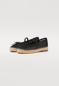 Ballerine espadrillas nere con suola in juta intrecciata, dettaglio a fiocco sulla punta e cinturino alla caviglia. Tessuto morbido con una leggera lucentezza.