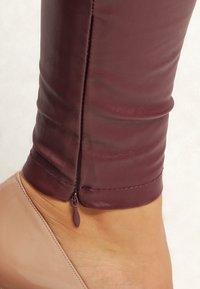 Bordowe legginsy z imitacji skóry o dopasowanym kroju, z ma�łym zamkiem błyskawicznym przy kostce i gładką, lekko błyszczącą teksturą.