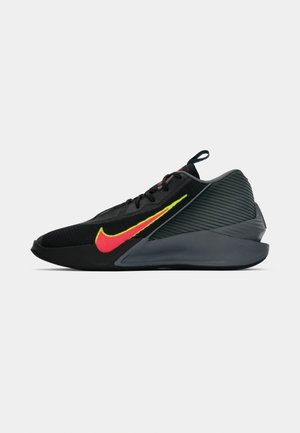 Shoe desportivo preto com parte superior texturizada, detalhes em vermelho e amarelo brilhante, design elegante e sola curva cinza. Apresenta atacadores e uma alça.