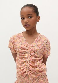 Bloemenprinttop met een V-hals, korte mouwen en geplooide details in roze, oranje en groene tinten, gemaakt van lichte stof.