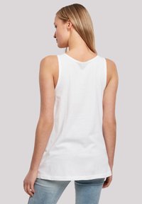 Weißes Tanktop aus weicher Baumwolle. Mit breiten Schulterträgern, einem runden Halsausschnitt und einem geraden Saum. Wird mit hellblauen Jeans kombiniert.