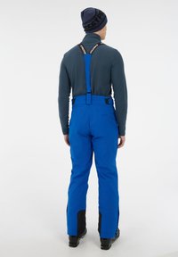 Modré snehové nohavice s nastaviteľnými čiernymi popruhmi a zosilnenými čiernymi detailmi na členkoch, vyrobené z vodeodolného materiálu.