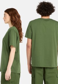 Gröna bomull t-shirts som visas från sidan och baksidan, med korta ärmar och en avslappnad passform. Enkelt design utan mönster eller logotyper.