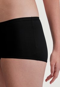 Zwarte sportshorts van gladde stof, met een lage tailleband, een aansluitend ontwerp en nette stiksels langs de randen.