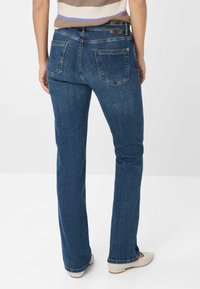 Vaqueros de denim azul oscuro con un diseño de pierna recta, que cuentan con dos bolsillos traseros y un ligero desgastado. La cinturilla tiene un acento de cuero.