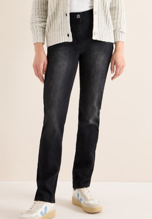 Jeans en denim noir avec une coupe slim, un léger dégradé et une fermeture à bouton. Associés à des baskets blanches avec des accents bleus.