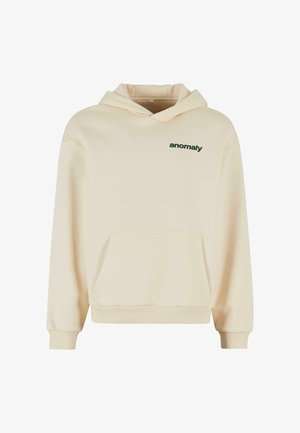 Kreemikapu, millel on esiküljel tasku ja rohelised "anomaalia" trükised rinna peal. Omab nööriga kapuutsi ja soonikkoes varrukaotsi. Pehme materjal.