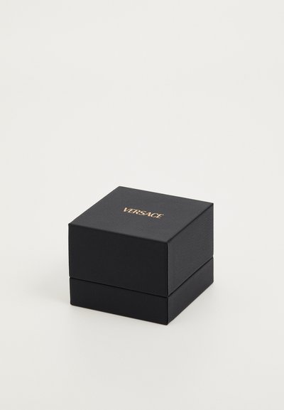Caja de regalo negra de Versace con un exterior texturizado. La parte superior presenta letras doradas en relieve. Forma cuadrada, diseño compacto con una tapa con bisagra.