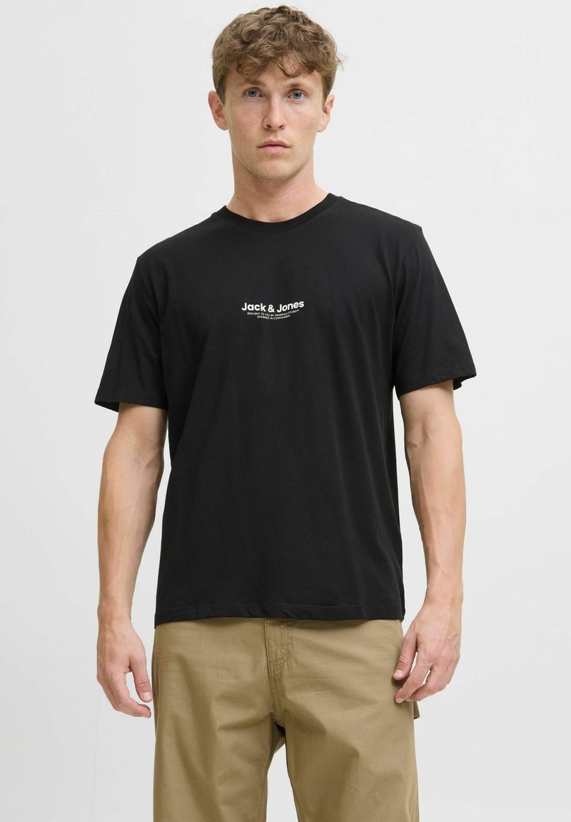Mustan värinen puuvillapaita lyhyillä hihoilla, johon on painettu valkoinen logo-teksti "Jack & Jones" rinnan kohdalle. Yksinkertainen muotoilu, tavallinen istuvuus.
