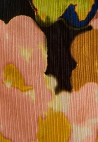 Tejido multicolor con un patrón floral que presenta acentos en rosa, amarillo, verde y negro. Texturizado con canalones verticales.