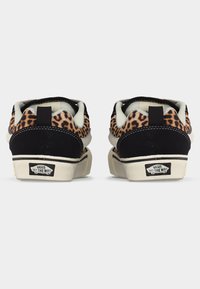 Ζευγάρι Vans παπουτσιών χαμηλού προφίλ με λεοπάρ σχέδιο και μαύρες λεπτομέρειες, από πίσω, με τα λογότυπα "Vans Off The Wall" στις σόλες.