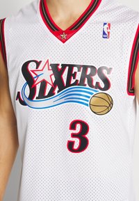 Valkoinen koripallopaita, jossa on punaiset ja mustat yksityiskohdat, "Sixers"-logo, kultainen koripallografiikka, NBA-logo sekä numero 3 etupuolella.