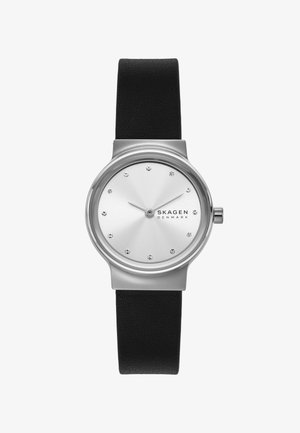 Minimalistisk Skagen armbåndsur med sølvfarvet rund urskive, krystal timemarkører, slanke visere og sort læderrem.