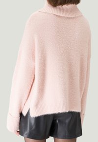 Hellrosa, flauschiger Pullover mit hohem, geripptem Kragen und übermäßig geschnittenen Schulternähten. Verfügt über einen entspannten Sitz und seitliche Schlitze am Saum.