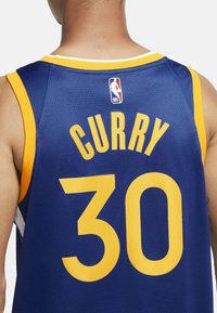 Modrý basketbalový dres se žlutými akcenty, s nápisem "CURRY" a číslem "30" na zadní straně. Obsahuje logo NBA na horní části.