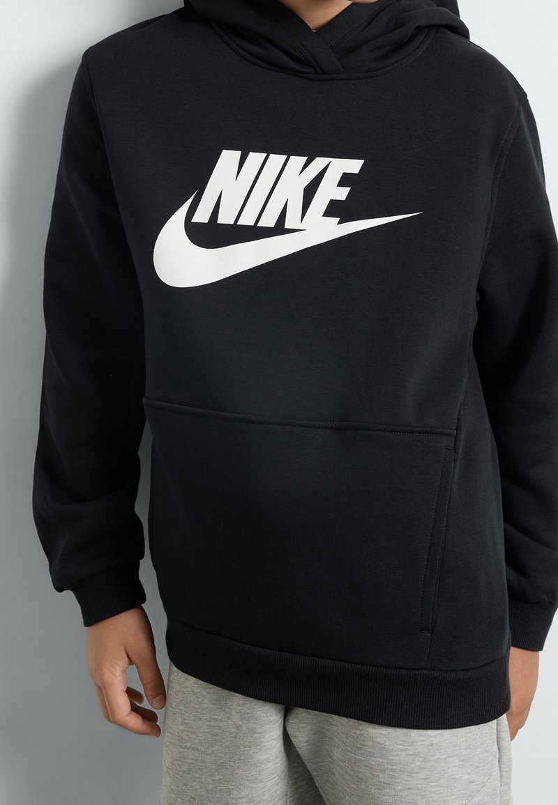 Černá mikina s kapucí vyrobená z měkké látky s velkým bílým logem Nike na přední straně. Obsahuje přední kapsu ve tvaru klokaního vaku a žebrované manžety.