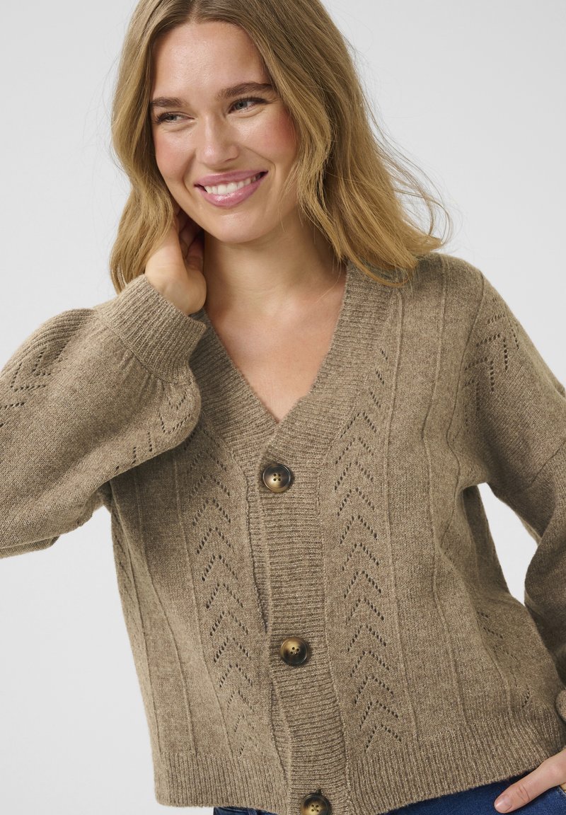 Cardigan tricoté marron avec un col en V, présentant un motif texturé, cinq boutons et des poignets côtelés. Matière douce en mélange de laine.