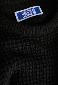 Black knitted jumper with a textured pattern. Features a white tag with blue lettering, reading "JACK & JONES" at the neckline.