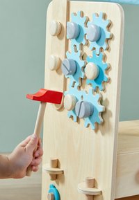 Houten activitypaneel met blauwe en grijze tandwielen, natuurlijke houten knoppen en een rode hamer. Glad oppervlak, eenvoudig ontwerp.