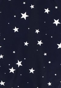 Tissu bleu marine présentant un motif éparpillé d'étoiles blanches de tailles variées. Texture lisse sans détails supplémentaires.