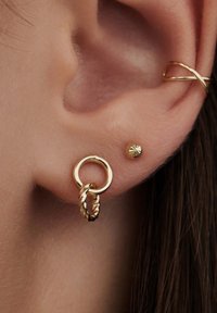 Goldohrringe mit einem runden Hoop und einem gedrehten Design sowie einem kleinen Schmuckstein mit strukturierter Oberfläche, der am Ohr befestigt ist.