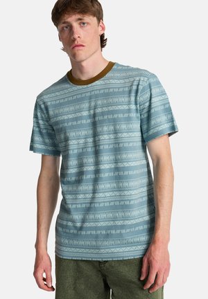 T-shirt azzurro chiaro con motivi geometrici, maniche corte e colletto marrone a contrasto; realizzata in tessuto morbido.