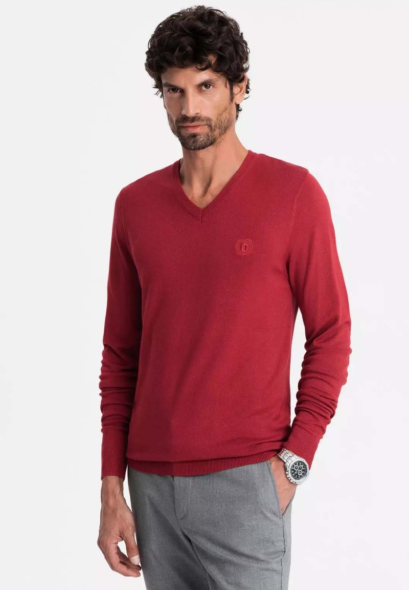 Maglione rosso lavorato a maglia con scollo a V e maniche lunghe, con una finitura testurizzata e un piccolo logo sul petto.