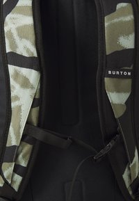 Backpack straps with green and beige camouflage pattern, black padding, and adjustable black buckle; "BURTON" label on right strap.