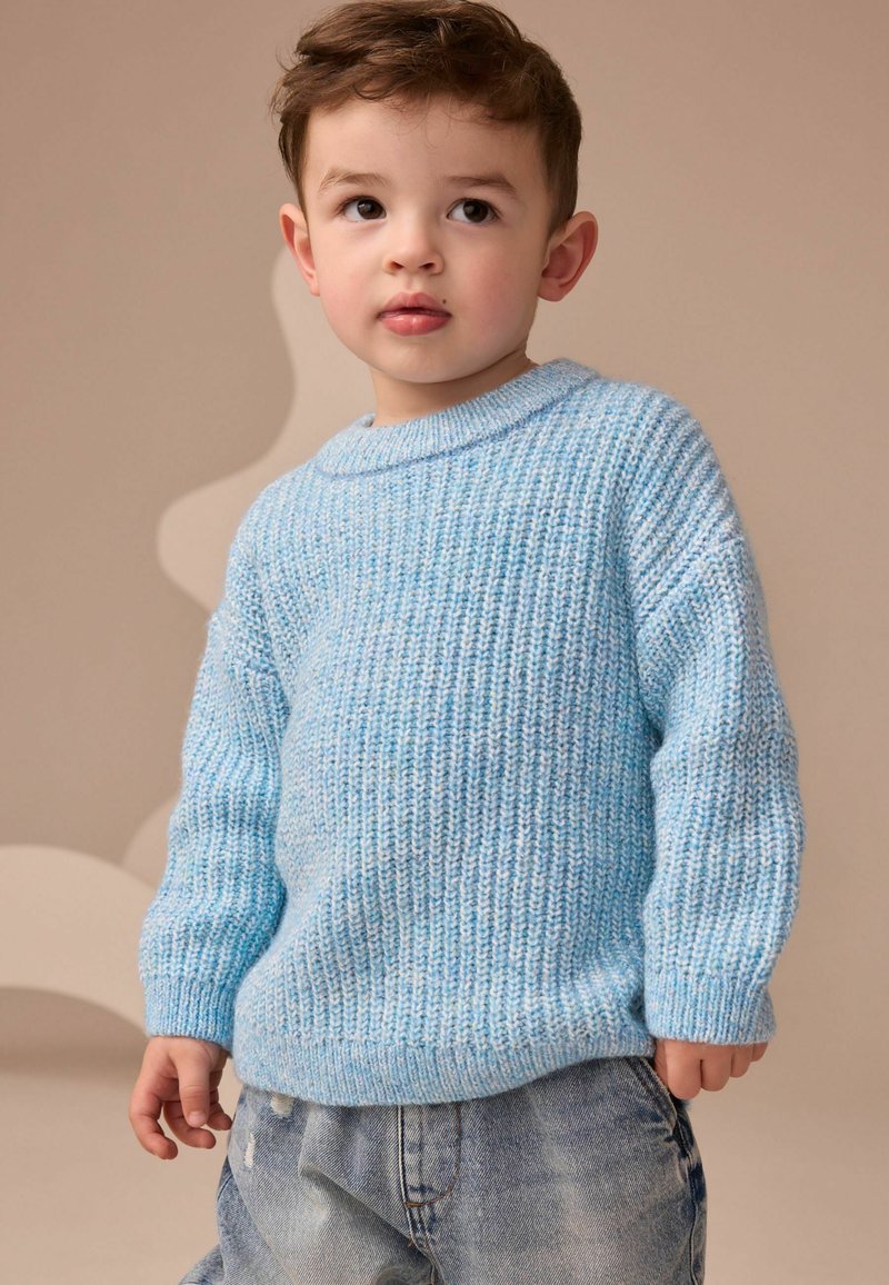 Maglione a maglia blu chiaro con texture a coste e scollatura rotonda, abbinato a jeans in denim blu chiaro.