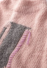 Stickad tyg i mjuk rosa och grå med en texturerad design. Har en dekorativ lila stygn och varierade mönster i stickningen.