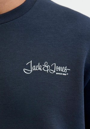 Tumesinine sviiter ribidega kaelusega; sisaldab valget tikandit "Jack & Jones" ja "SINCE 1990." Pehme tekstuur, vabaltaja disain.