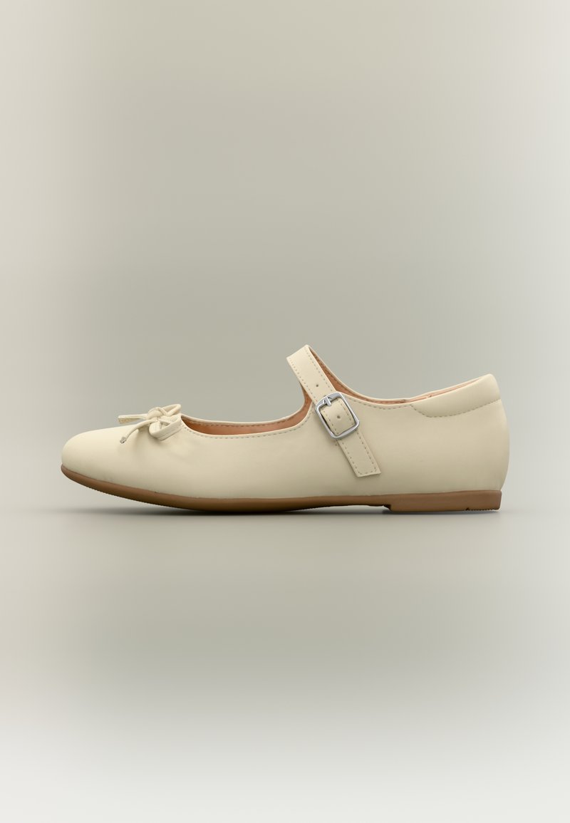 Ballerine beige avec un bout arrondi, un nœud à l'avant et une bride ajustable avec une boucle argentée. Texture en cuir lisse.