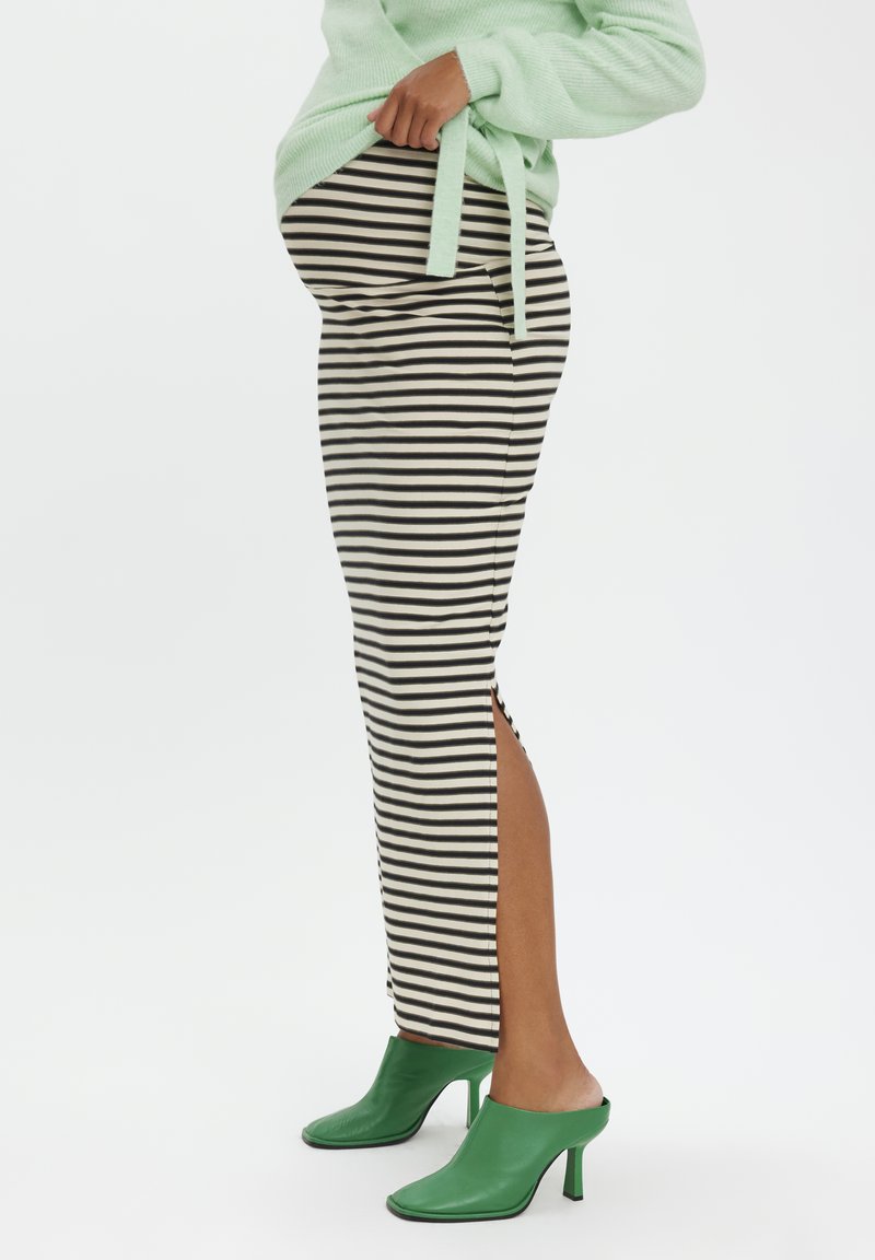 Stribet sort og hvid nederdel med sideslid, parret med grønne hælede mules og en lysegrøn sweater. Glat stof med tætsiddende design.