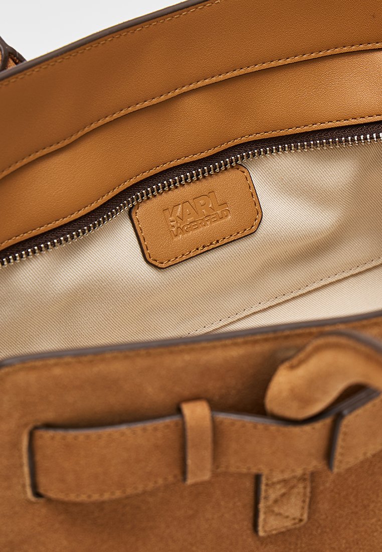 Interior de bolso de cuero curtido y ante con un bolsillo con cremallera y una etiqueta con el logo "KARL LAGERFELD" en relieve.