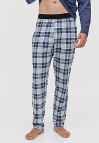 Pajama do materiału w kratę w kolorze granatowym, jasnoniebieskim i białym; wykonane z miękkiej tkaniny z elastycznym czarnym paskiem w talii. Prosty krój nogawek.