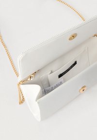 Λευκό τσαντάκι χειρός από συνθετικό δέρμα με χρυσή αλυσίδα, κλείσιμο με κουμπί και εσωτερικές θήκες για κάρτες. Λείο υλικό με διακριτική γυαλάδα.