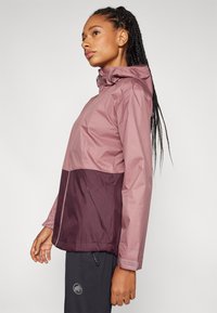 Lightweight, waterproof jacket with a pink top and dark burgundy bottom. Features a hood, zip closure, and elastic cuffs.