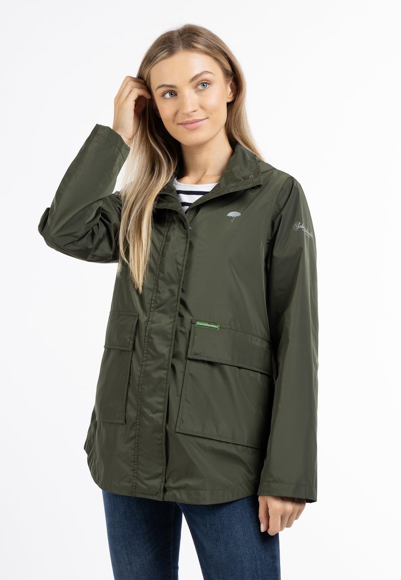 Olivgrüne wasserdichte Jacke mit Reißverschluss, zwei Fronttaschen und Kapuze. Verfügt über ein hellgraues Logo auf der Brust und ein grünes Etikett.