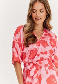 Růžovo-červené tie-dye šaty s krátkými rukávy, V-výstřihem a páskem v pase. Hladká tkanina s volným střihem a jemným leskem.