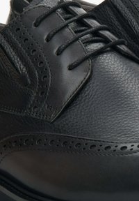 Czarne skórzane buty oxford z teksturowaną powierzchnią, szczegółowymi perforacjami wzdłuż boków i płaskimi sznurowadłami; zaokrąglony nos.