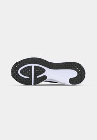 Sports shoe outsole featuring a black textured rubber surface with a white midsole, designed with circular and oval traction patterns.