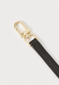 Bracelet en cuir noir avec fermoir en métal doré. Le bracelet présente une texture lisse avec un détail de surpiqûres ; le fermoir a un design rond et sécurisé.
