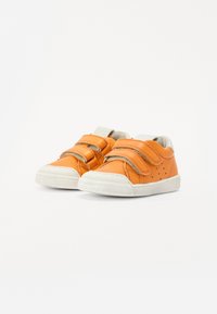 Oranžid nahked kahe velcro rihmaga, valge kummitald, ümmargune varvas ja külgedel väikesed augud hingavuse tagamiseks.
