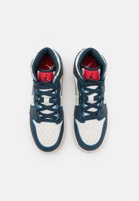 Granatowe i białe sneakersy z siateczkową górą, perforowanym noskiem, niebieskimi akcentami i czerwonym wnętrzem. Posiadają logo na pięcie i języku.